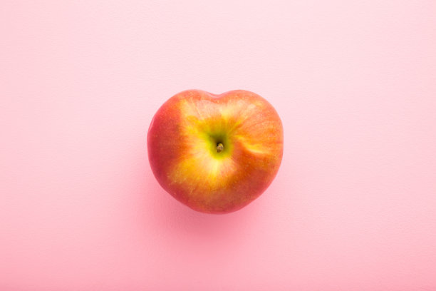 心形的红苹果在浅粉色的桌子背景上。新鲜水果。柔和的颜色。特写镜头。自顶向下的观点。图片下载