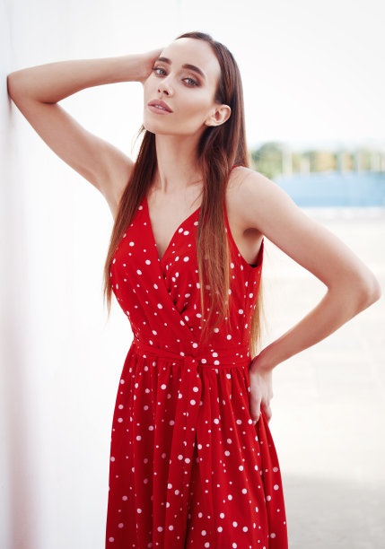 街头时尚:美丽性感的女孩穿着红色的裙子。可爱的年轻女子站在墙上的肖像图片下载