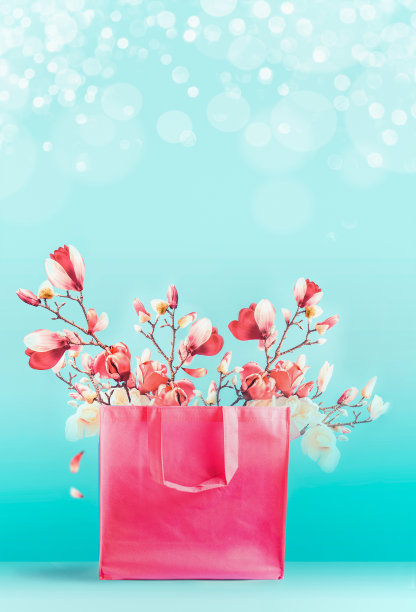 购物袋与春天的花枝站在蓝绿色的背景。时髦的活珊瑚色。创造性的春天图片下载
