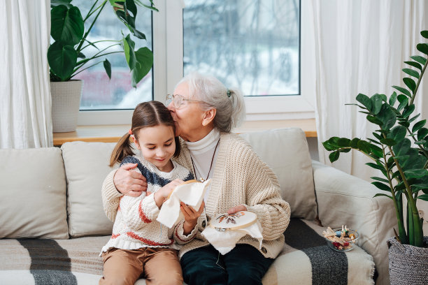 慈爱的奶奶亲吻她的孙女，他们在一起刺绣图片下载