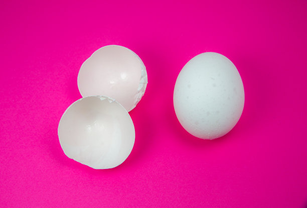 粉红色的背景上是白色的鸡蛋和蛋壳。副本的空间。极简主义，原创和创意的照片。漂亮的壁纸。复活节假期。图片下载