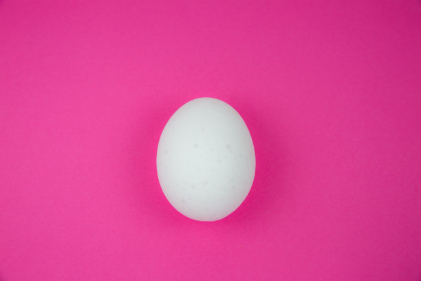 粉红色背景上的白色鸡蛋。副本的空间。极简主义，原创和创意的照片。漂亮的壁纸。复活节假期。图片下载