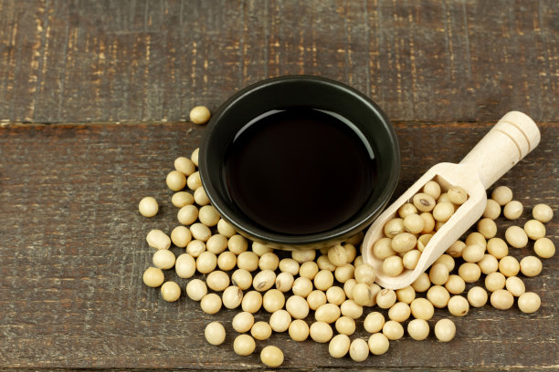 小黑碗里装酱油，木勺上放黄豆。图片下载