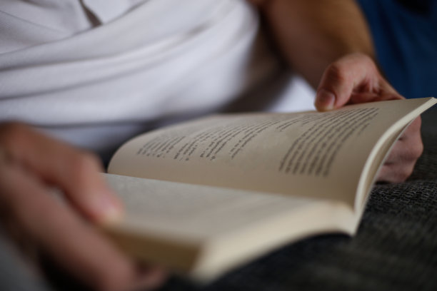 近距离的年轻人的手握和阅读的书。图片下载