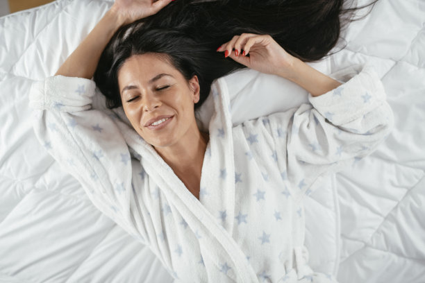 美丽的年轻女子在床上放松早上。库存图片图片下载