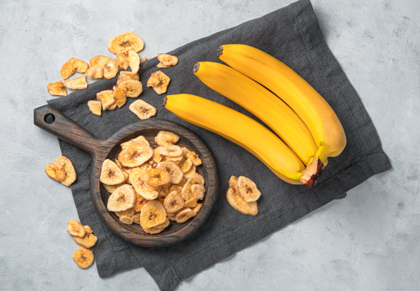 水果，天然甜点:香蕉片。灰色背景上是几片干香蕉和新鲜水果图片下载