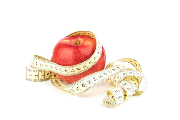 用卷尺绕着白底上的红苹果。图片下载