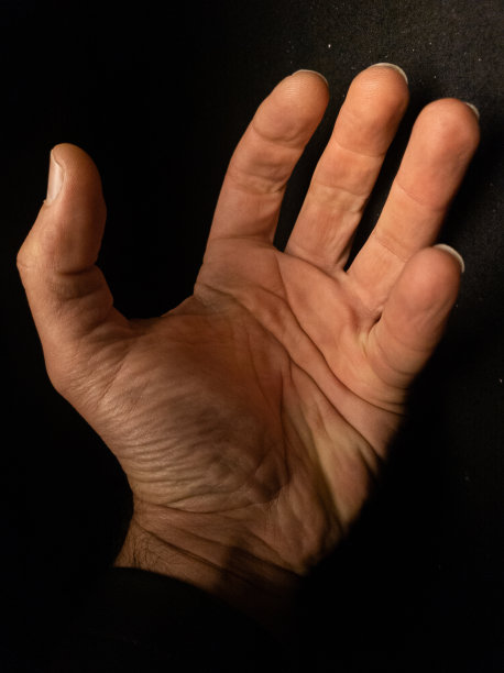 在黑暗的背景下打开人的手掌。图片下载