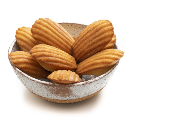 自制的玛德琳蛋糕放在碗里，新鲜烘烤，单独放在白色的蛋糕上图片下载