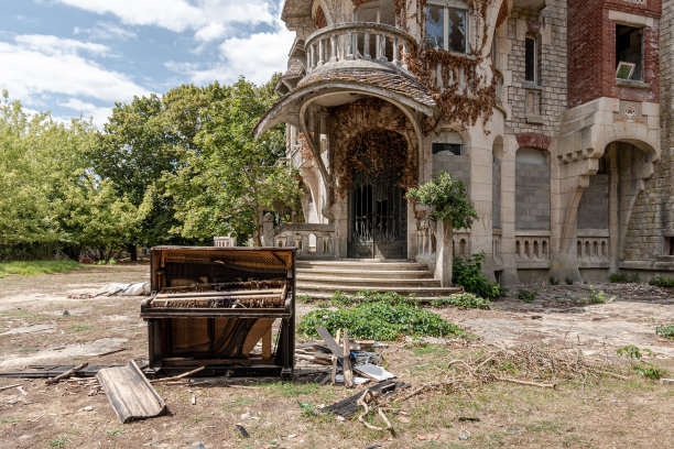 一所废弃的房子前面的花园里有一架坏掉的黑色钢琴图片下载