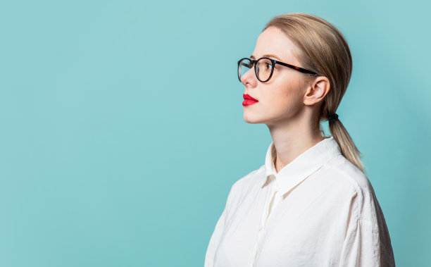 侧面美丽的金发在白色的衬衫在蓝色的背景图片下载