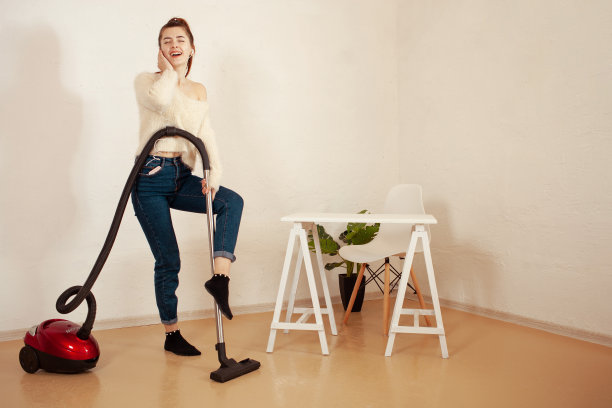 一个正在打扫屋子的年轻女孩。一个妇女用真空吸尘器吸地板。副本的空间。听音乐图片下载