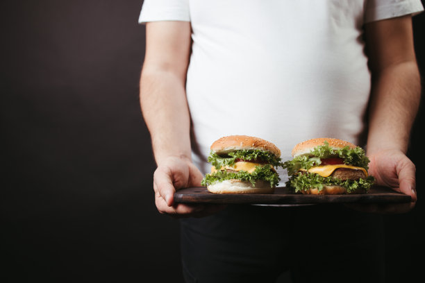 饮食过量。有两个大汉堡的胖子图片下载