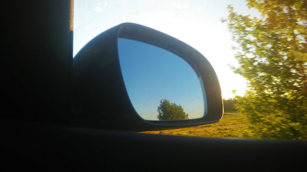 从汽车的后视镜看。仪表板。挡风玻璃。多媒体系统。太阳。大自然。侧窗。一面镜子。图片下载