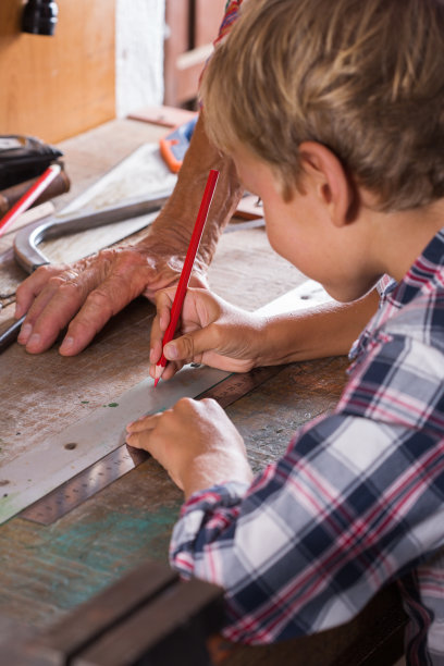 祖父教男孩用细木工工具在长凳上干活图片下载