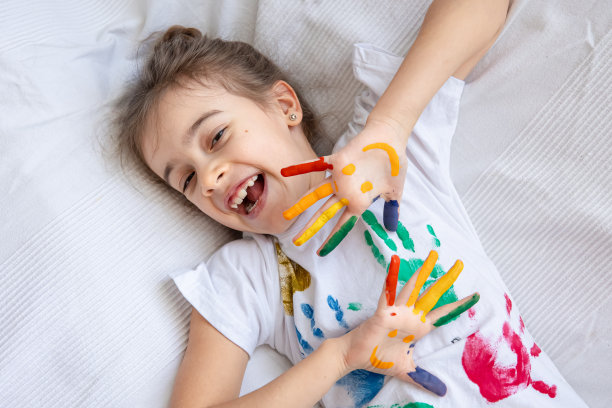 一个快乐的孩子的彩色手掌的特写，用颜料画。图片下载