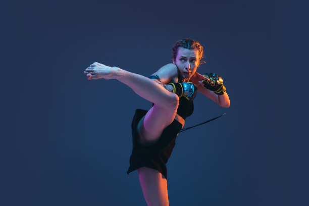 年轻女子综合格斗选手在霓虹灯下的蓝色背景下摆出孤立的姿势图片下载
