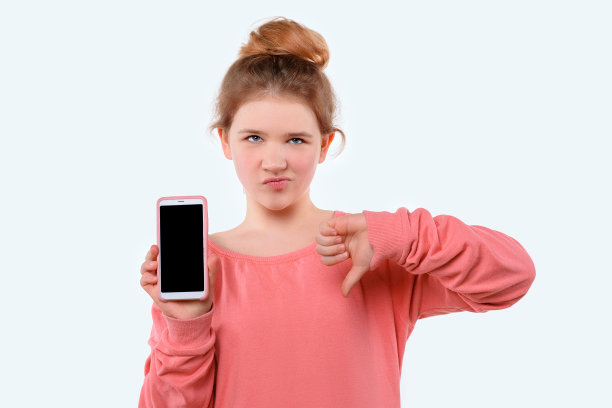 一个可爱的小女孩拿着智能手机，拇指朝下。白色背景图片下载