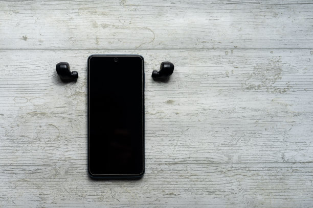 智能手机和黑色无线耳机，白色木质背景的充电器图片下载