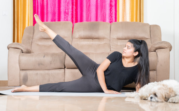 小女孩和她的宠物在家里的瑜伽垫上做运动——新冠肺炎大流行带来的新常态健康生活方式的概念。图片下载