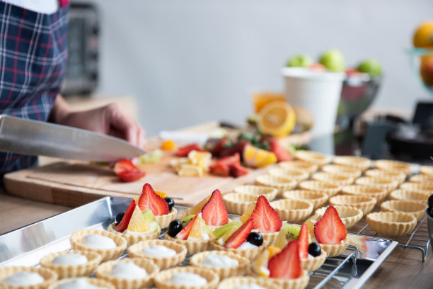 亚洲妇女在家庭厨房制作水果挞甜点，供网上销售图片下载