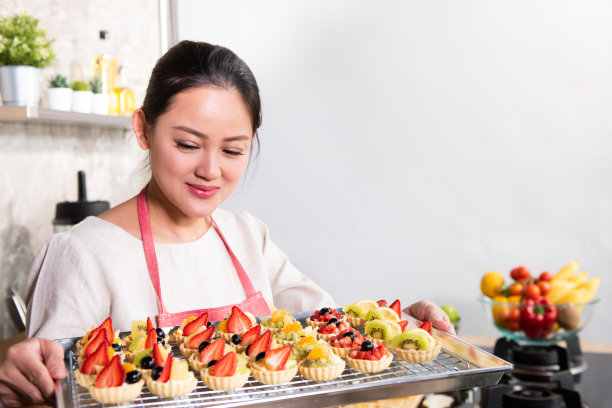 亚洲妇女在家庭厨房制作水果挞甜点，供网上销售图片下载