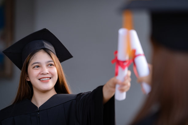 年轻快乐的亚洲女子大学毕业生在毕业礼服和学位证书持有学位证书庆祝教育成就在大学校园。教育库存图片图片下载
