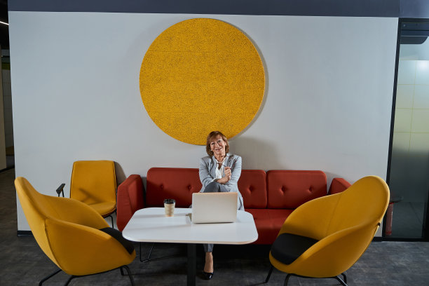 手提电脑前的女士，拿着眼镜，对着相机微笑图片下载