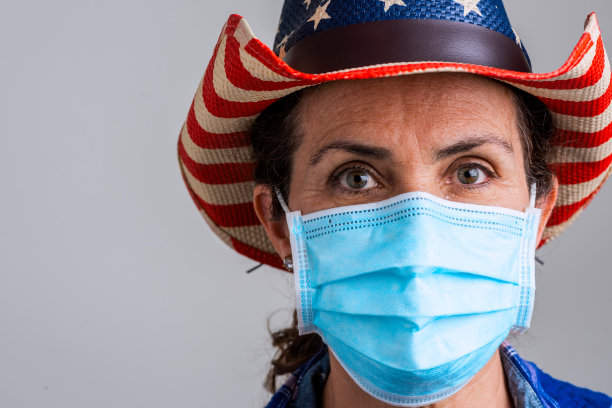 沉思的成熟的美国白人妇女，戴着一个保护面罩，戴着一顶牛仔帽图片下载