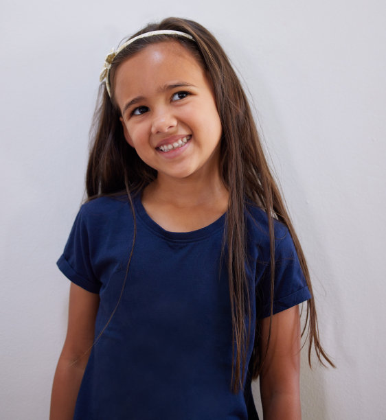 一个可爱的小女孩靠在墙上摆姿势图片下载