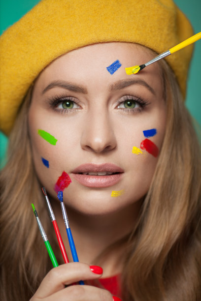 一个女人的肖像，用彩色的颜料刷在脸上。明亮的绿色眼睛。图片下载