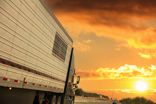 高速公路上的卡车，侧视图。货物运输的概念。日出时多云的天空图片下载