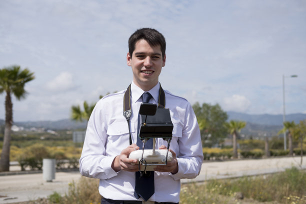 一个穿着飞行学校制服的年轻人，手里拿着一架无人机图片下载