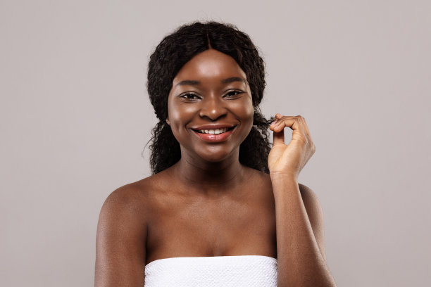 可爱美丽的非洲女性与自然卷曲的头发摆姿势在灰色的背景图片下载