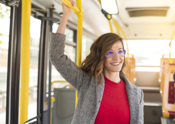 一位年轻女子站在公共汽车上微笑着旅行。图片下载