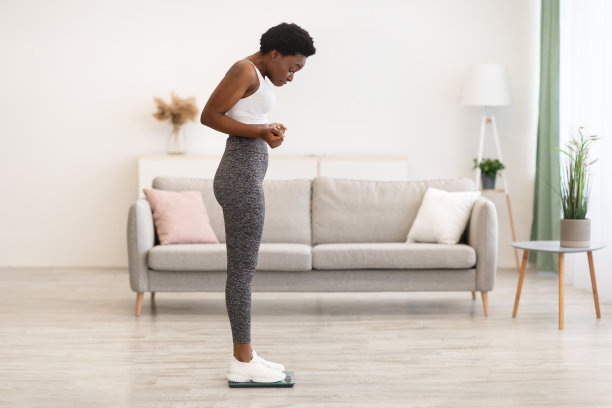 室内，黑人女性体重增加后站在秤上称重图片下载