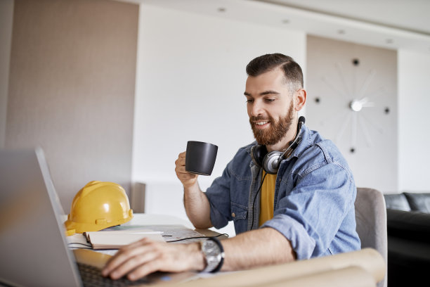 一个年轻人在他的笔记本电脑上工作，喝着咖啡在家办公图片下载