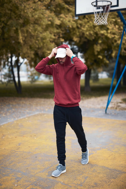 运动男子在城市公园/篮球场训练帽衫。图片下载