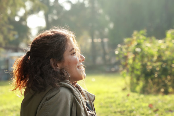 美丽的年轻女子坐在公园的绿色草地上的肖像图片下载