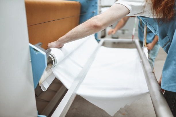 纺织厂工人把纺织材料放在印刷滚筒上图片下载