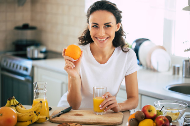 可爱美丽和快乐年轻的黑发女人在厨房在家准备水果素食沙拉或一个健康的冰沙和有乐趣图片下载