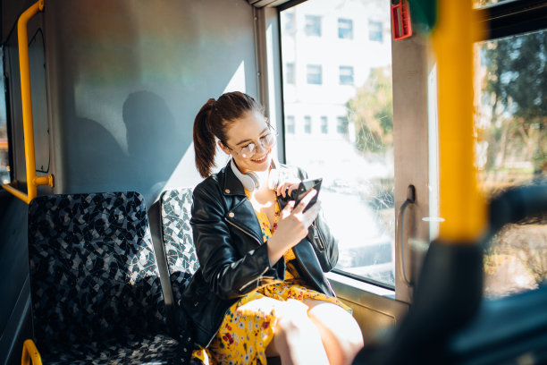 一名年轻女子在公交车上一边发短信一边听音乐图片下载