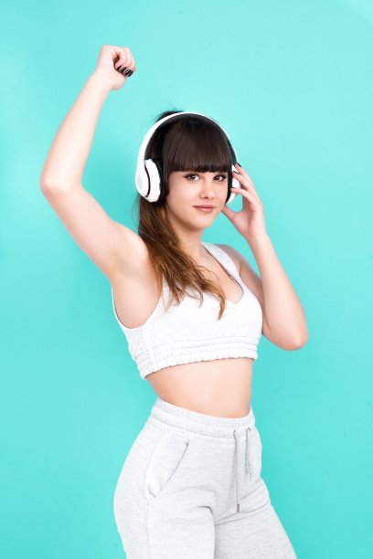 女人戴着耳机在蓝色背景愉快地享受着音乐图片下载