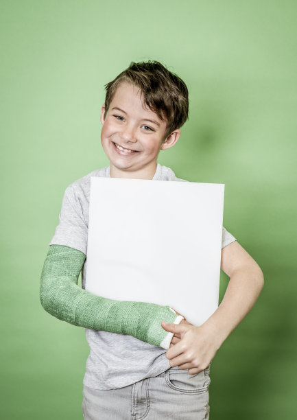 男孩用绿色的手石膏拿着白板在绿色的背景图片下载