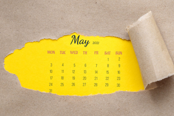 2021年5月。整个月的日历页。纸上有个洞，边缘被撕掉了。黄色背景透过参差不齐的孔可见。概念日历日期，时间计划，会议，事件。图片下载