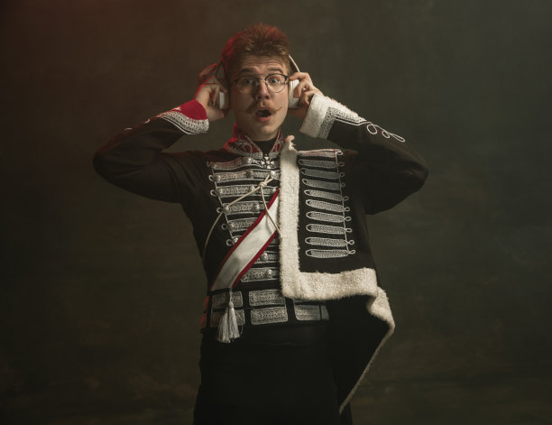 年轻男子在西装皇家人孤立在深绿色的背景。复古风格，比较时代的概念。漂亮的男模像历史人物，君主，守旧。图片下载