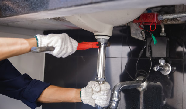 水管工人用活动扳手固定白色沉管。图片下载