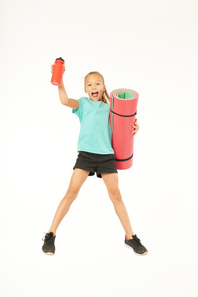 带着瑜伽垫和水瓶子的可爱女孩在工作室里跳图片下载