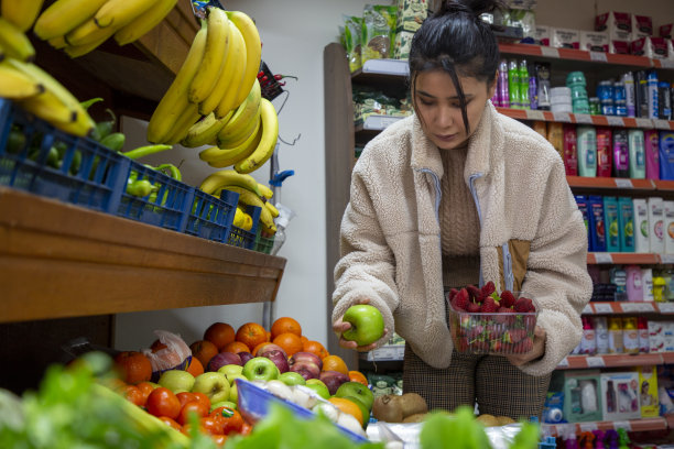 年轻的亚洲女人在杂货店买水果图片下载