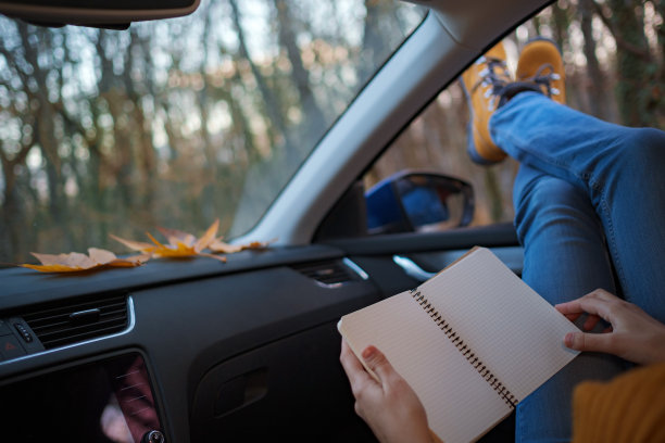 女人的脚踩在车门上。在日落森林的窗外图片下载
